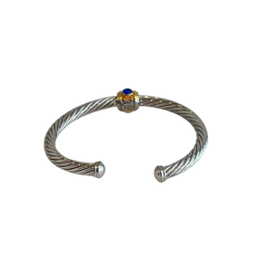 Back of silver David Yurman Renaissance Cable Bracelet with gold accents and a blue stone on a white background. 