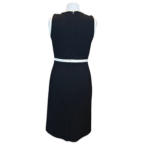 A sleeveless black sheath dress shown from the back on a white mannequin torso, featuring a contrasting white waistband detail.