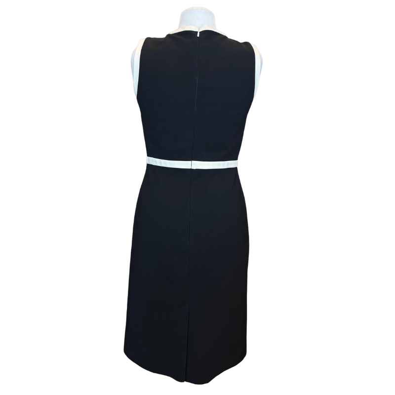 A sleeveless black sheath dress shown from the back on a white mannequin torso, featuring a contrasting white waistband detail.