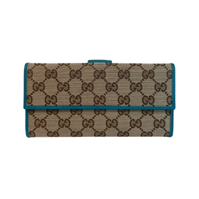 A Gucci monogram canvas clutch wallet with a teal blue leather trim and a small top tab closure, shown against a plain white background.