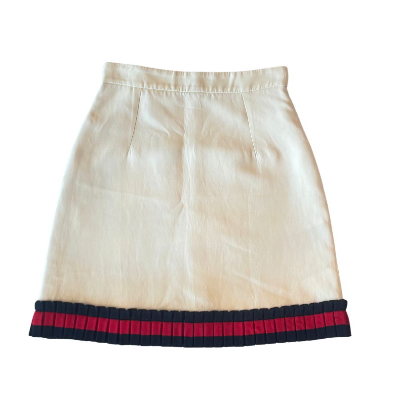 An off-white or cream-colored skirt with a pleated red and navy blue striped hem, shown flat against a white background.