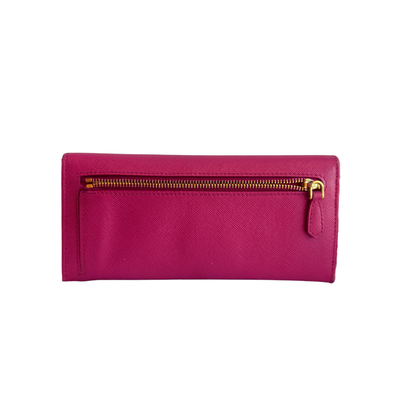 Back of a magenta pink textured leather  wallet with a gold-tone zipper and pull tab, shown against a plain white background.