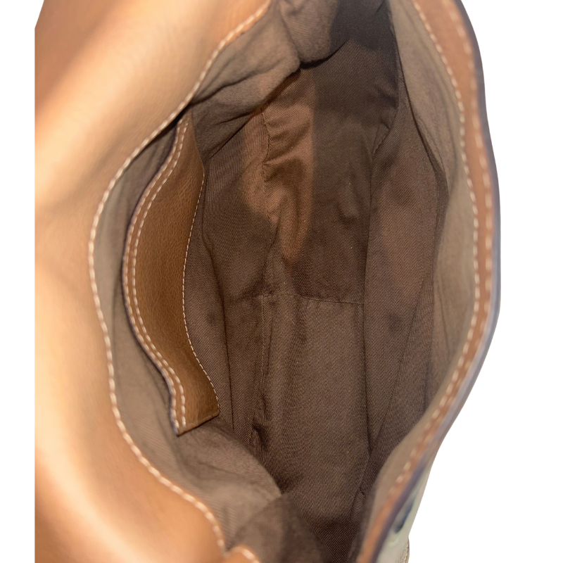 Close-up of the interior of a tan leather bag, showing a brown fabric lining with contrast stitching.