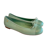 A pair of Chanel ballet flats in a light mint green patent leather, featuring a glossy cap toe, delicate bow details, and the signature interlocking CC logo on the side.