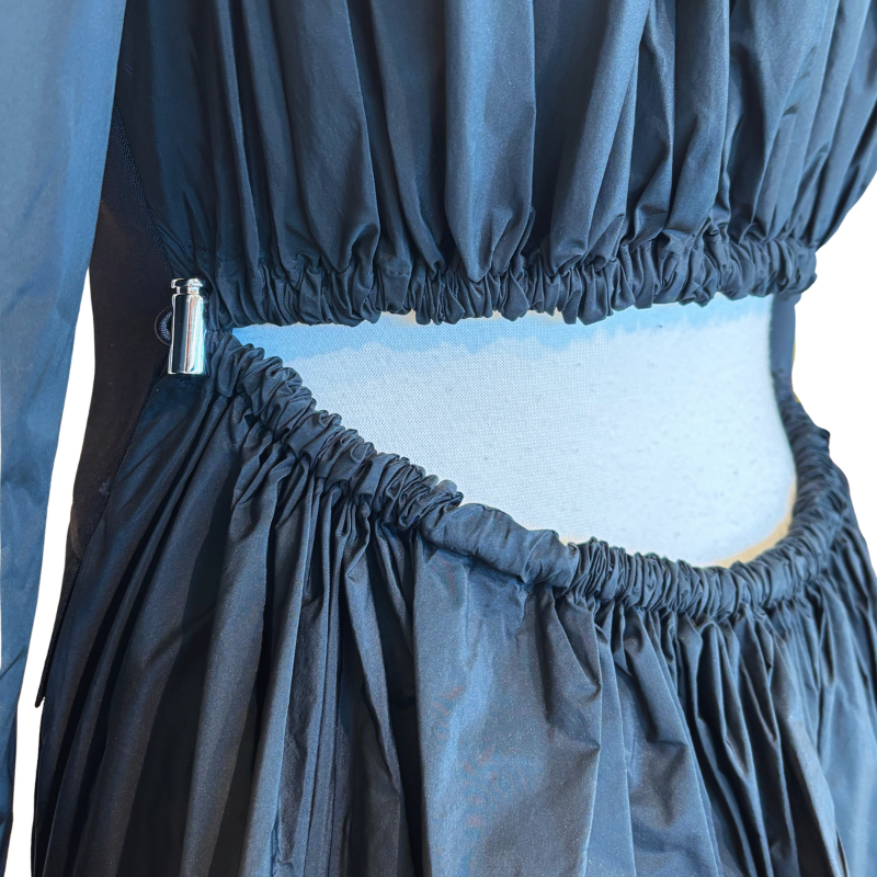 Close-up of a dark navy or black ruched fabric garment with elasticized gathered waist and hip details, shown on a mannequin torso against a white background.