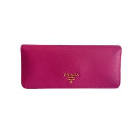 A Prada wallet in magenta pink Saffiano leather with a gold-tone logo on the front, set against a plain white background.
