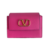 A bright pink textured leather wallet with a gold-tone metal 'V' logo clasp, shown against a plain white background.