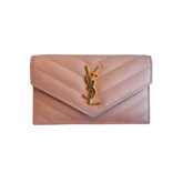 A Saint Laurent pouch in light pink pebbled leather with a gold-tone YSL logo clasp, shown against a plain white background.