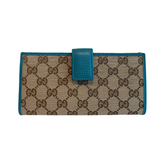 A Gucci monogram canvas wallet with teal leather trim and a matching teal leather tab closure, shown against a plain white background.