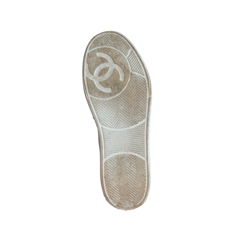 The outsole of a white sneaker, showing the embossed interlocking CC logo of Chanel, photographed from a top-down view on a white background.