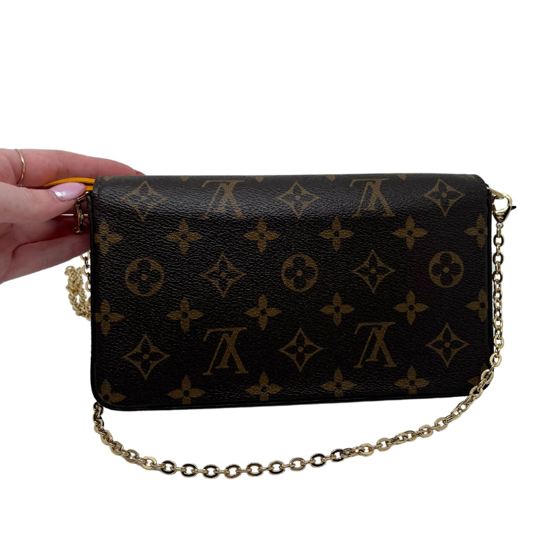 Louis Vuitton Vivienne New York Soho Felicie Pochette  Monogram Canvas Exterior   Printed Image on Front Exterior   Gold Toned Hardware  Single Gold Chain Shoulder Strap   Front Flap   Button Closure   Mustard Canvas Interior   Two Removable Interior Wallets   One with Brown Monogram Canvas Exterior, Zip Closure, and Mustard Canvas Interior   One with Mustard Interior and Exterior, 8 Card Pockets, One Large Pocket with no Closure  One Interior Flat Pocket 