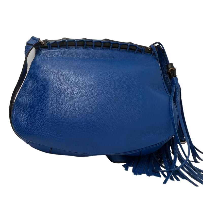 Back View:Blue Leather, Flap Bag, Two Tassels, Bamboo Top and Accents, Adjustable Leather Shoulder Strap. 