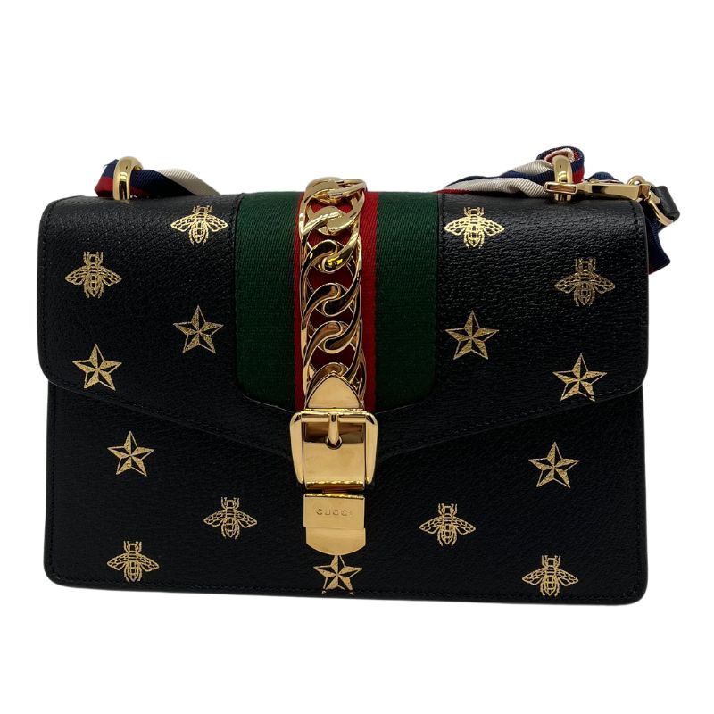 Gucci Sylvie Printed Small Shoulder Bag, black leather with metallic gold print, gold tone hardware with chain detail, red and green detail, removable and adjustable black leather shoulder strap, and adjustable grosgrain ribbon strap. Excellent new condition