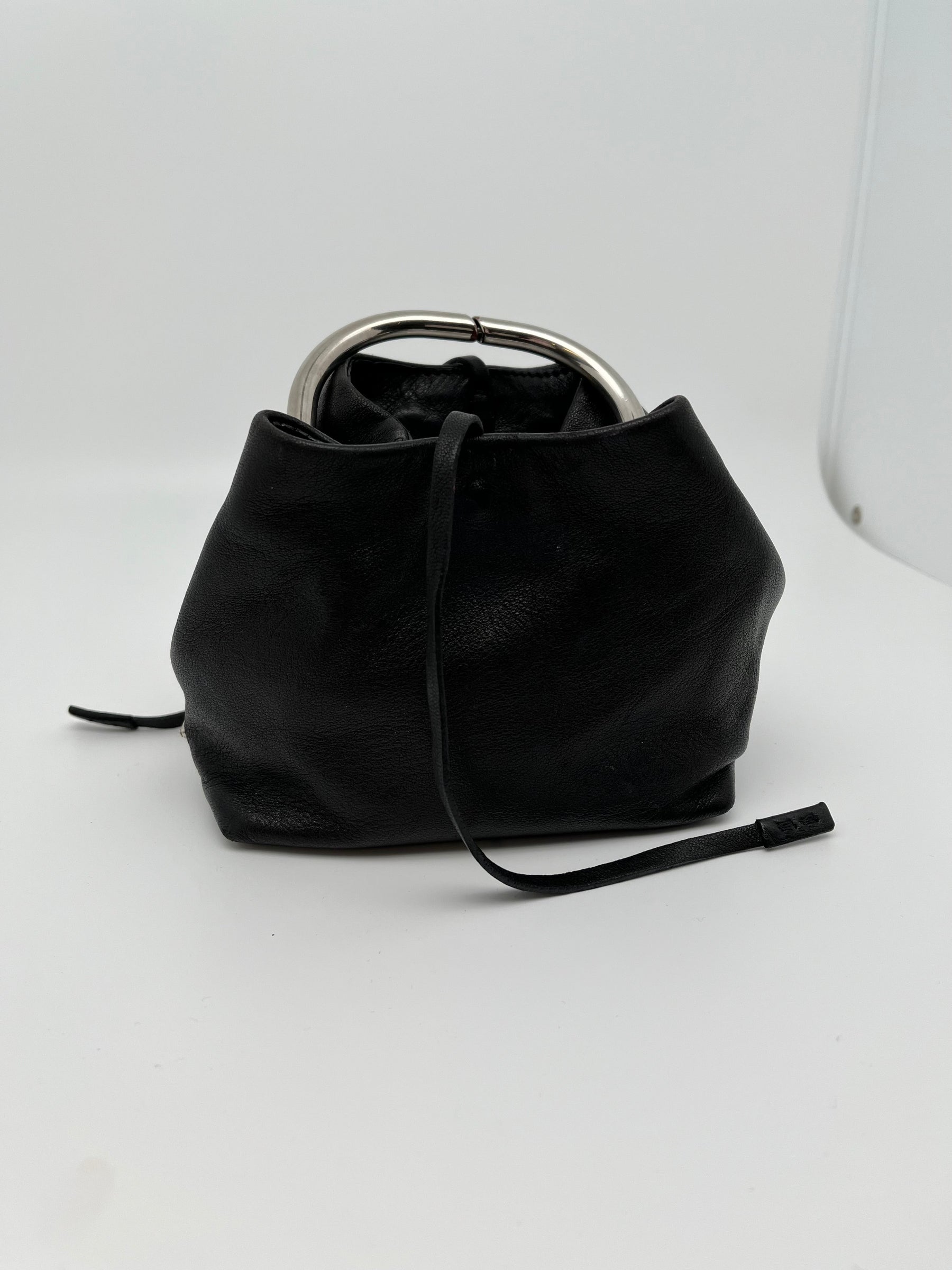 Prada Black Leather O-Ring Mini Top Handle Bag | Silver Tone Hardware | Prada Plaque | Leather String Tie Closure | Yellow Moire Satin Lining | Zippered Interior Pocket | Great Condition