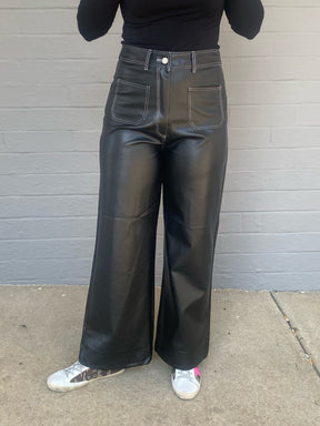 Womens black faux leather wide leg pants, wide stitching around waistband and pockets, high waisted, belt loops around waist, zipper and button closure, front and back pockets, front view