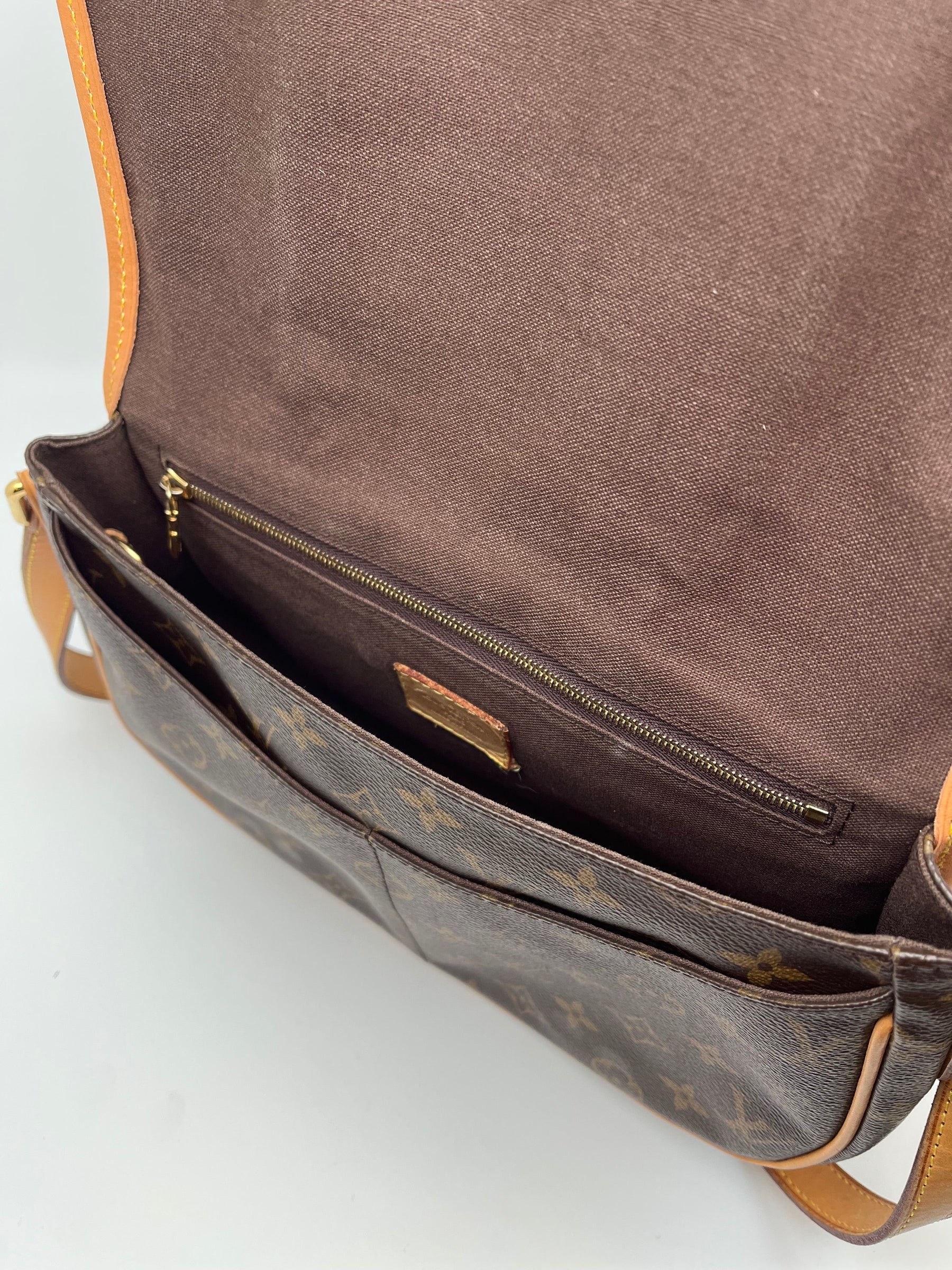 Louis Vuitton Menilmontant with Brown Monogram, brass hardware, and leather trim. Canvas interior with three interior pockets and magnetic closure. Great condition