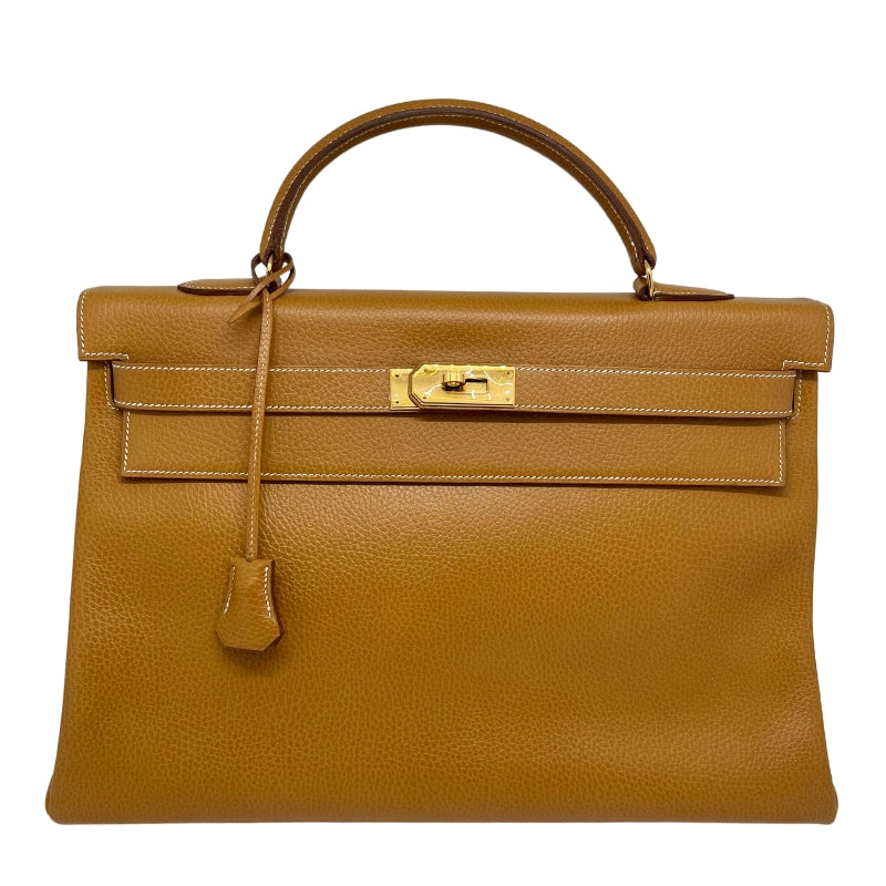 Hermès Ardennes Kelly Retourne 35  Top Handle Bag  Gold Ardennes Leather  Gold-Plated Hardware  Front Turn-Lock Closure  Protective Feet  Includes Lock, Keys & Clochette  Chevre Goatskin Interior  Two Interior Flat Pockets   One Interior Zipper Pocket  Dust Bag Included