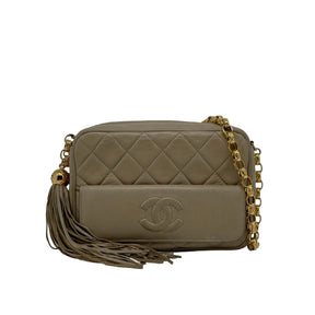 Chanel Lambskin Vintage CC Camera Bag   Beige Lambskin Leather Exterior  CC Stitched Emblem   Gold Toned Hardware  Chain-link Shoulder Strap   Tassel Accent  Single Exterior Pocket   Zip Top Closure  Leather Interior  Single Interior Zipper Pocket