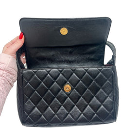 Chanel Quilted Leather Shoulder Bag  Black Leather Exterior   Gold Toned Hardware   Single Exterior Back Pocket with Burgundy Exterior   Single Quilted Leather Shoulder Strap  Front Flap Enclosure with Button Clasp  Chanel Monogram Emblem  Black and Burgundy Leather Interior   Double Interior Pockets on one Side 