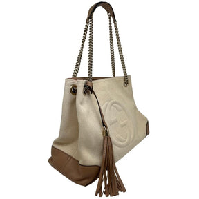 Gucci canvas soho chain tote, beige canvas exterior, chain dual shoulder strap, brown leather embellishments, brown leather tassel, silver tone hardware, GG logo stitched on front, canvas lining, three interior pockets, top clasp closure, condition good, side view